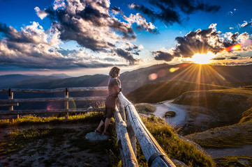 Girl leaning against the fence watching a beautiful sunset in a peaceful and tranquil place, Mount...