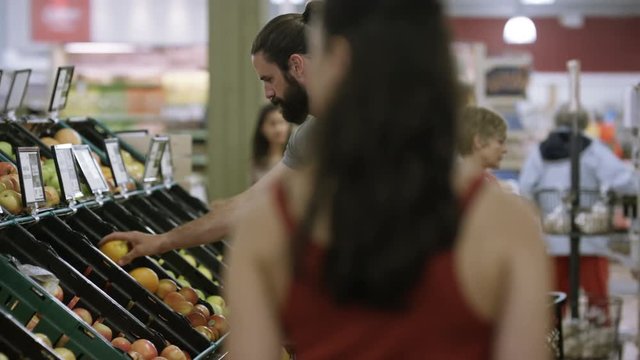  Cheerful worker in grocery store juggling oranges