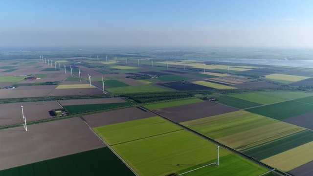 Bird view aerial of polder landscape showing different colors of the farm land and also showing wind turbines providing renewable energy from wind typical dutch flat land far horizon 4k quality