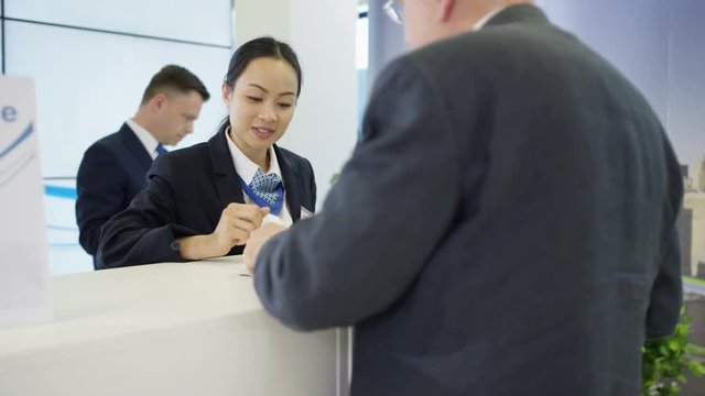  Bank worker at service desk taking cash deposit from a customer