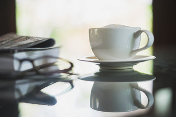A white cup of coffee on glass table
