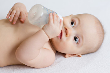 Cute baby with milk bottle on white blanket