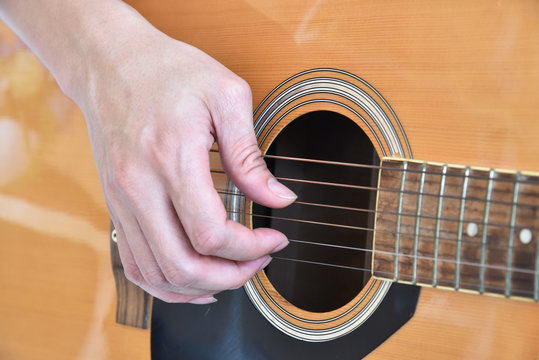 Close-up Hand of young man playing acoustic guitar at home