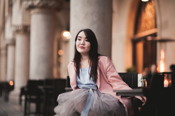Beautiful Asian girl model in dress sitting at the old city background