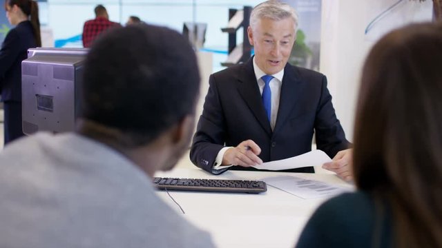  Modern city bank, adviser assisting couple & getting signature on document