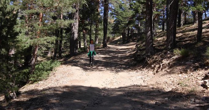 4k video. Brunette sport woman with white shirt grey trousers walking or hiking or trekking on rural path in Navacerrada mountain, in Guadarrama Natural Park, Madrid, Spain 
