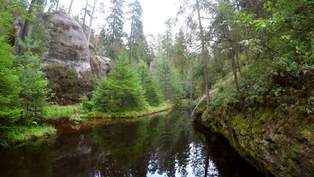 Reflection of forest in small lake in the rock mountain Adrspasske skaly, Czech republic