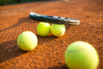 Close up view of tennis racket and balls on the clay tennis court, recreational sport