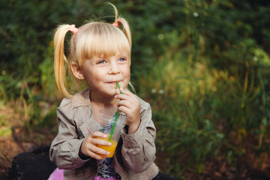 Beautiful little girl drinking orange juice