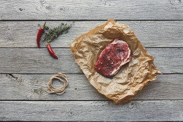 Raw beef steak on dark wooden table background, top view