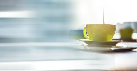Green coffee cup on desk and blurry blue transition
