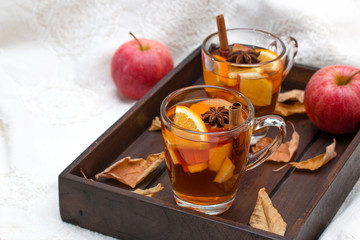 Glass mug ot hot spicy drink with fruits on dark wooden tray. Autumn style photo.