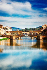 Obraz premium Ponte Santa Trinita bridge over the Arno River with cloudy sky and reflections, Florence, Italy, retro toned