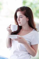 young woman drinking coffee outdoor on balcony