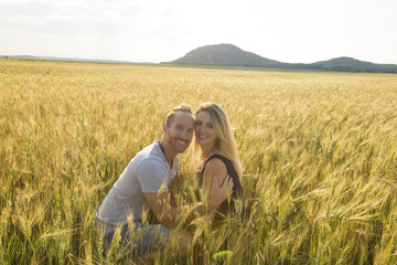 Naklejka na ściany i meble Young couple in a romantic place. Couple in love outdoors in a wheat field embracing