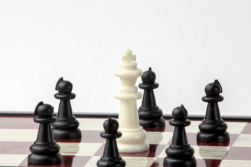 chess white queen, surrounded by black pawns. concept of struggle. Isolated on white background.