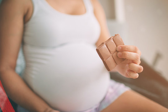 Pregnant Woman Enjoying Of Eating Chocolate At Home