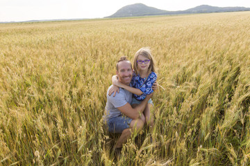portrait of a father and daughter playing in the wheat field at sunset.