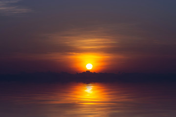 Sunrise on the sky and dark cloud at the lake.