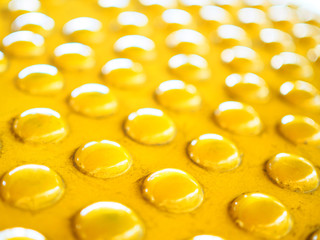 Perspective bright shiny dirty stained yellow embossed round dot pattern plastic disc plate, bright sunlight reflection background, selective focus