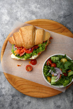 Breakfast croissant with salmon and salad bowl