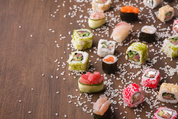 Set of sushi, maki and rolls with sesame on wooden rustic background