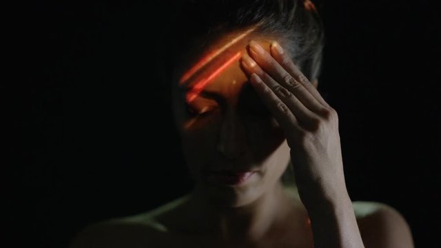 Light projected onto woman's face indicating brain activity or migraine