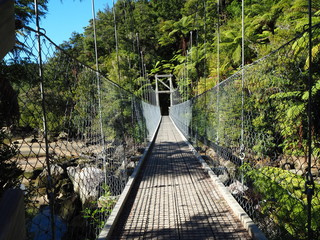 Fototapeta na wymiar Hängebrücke im Abel Tasman Nationalpark mit grünen Bäumen im Hintergrund, Neuseeland