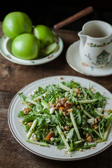 A gourmet salad with arugula and green apples on rustic surface, vertical,
