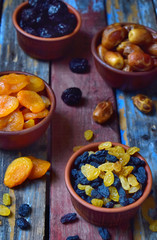Composition from different varieties of dried fruits on wooden background - dates, apricots, prunes, raisins. Healthy food