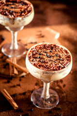 tiramisu in a glass decorated with coffee beans on a dark background