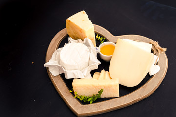 various types of cheese on a stand in the shape of a heart, concept elegant life and love cheese, top view