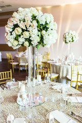 Large vase with beautiful roses stands on rich decorated wedding table