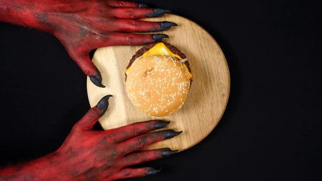 Red demon hands gives a burger to the woman.
