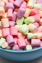 Colorful mini marshmallows in a blue bowl as background, macro. Fluffy marshmallows texture and pattern. High Resolution image, Soft focus
