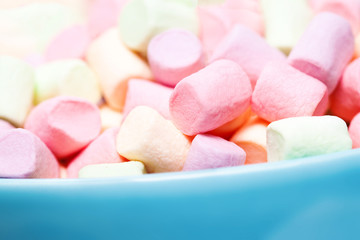 Colorful mini marshmallows in a blue bowl as background, macro. Fluffy marshmallows texture and pattern. High Resolution image, Soft focus