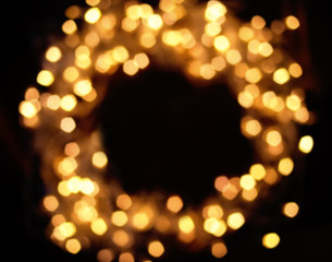 Blur Christmas lights garland on dark  background, holiday card concept. Defocured circle festive lights. Blurred lights in wreath shape.