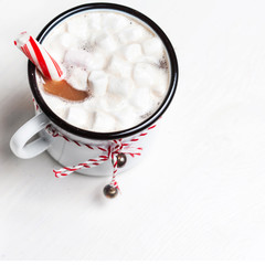 Hot chocolate mug  with marshmallow with sweet red candy striped stick. Vintage mug of winter cocoa with cinnamon stick. Christmas cozy home concept