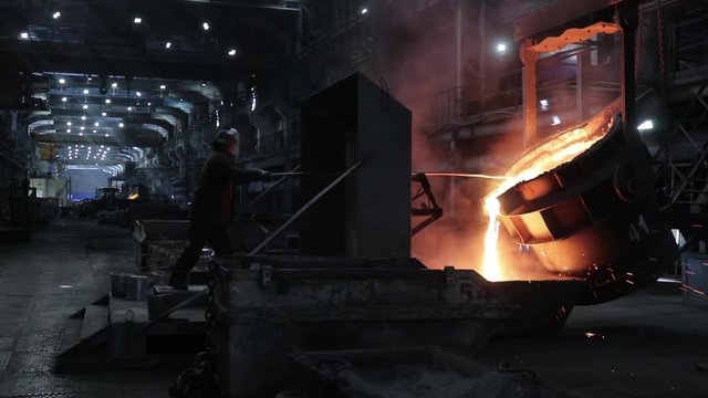 Production process at a steel mill. Open fire. Rays of light through the dust and air of the workshop. Human hard work in Siberia.