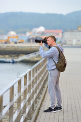 young man takes pictures of the sea from the waterfront