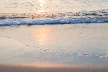Sunset soft beautiful ocean wave on sandy beach. romantic travel background.