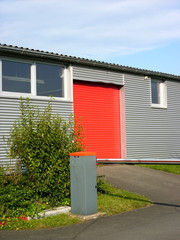 Rotes Rolltor einer modernen Flugzeughalle mit silberner Fassade aus Wellblech am Segelflugplatz von Oerlinghausen bei Bielefeld am Hermannsweg im Teutoburger Wald in Ostwestfalen-Lippe