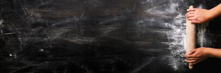 Fototapeten Mädchenhände halten Nudelholz mit Mehl auf dunkelschwarzem Tisch, Backhintergrund, Draufsicht, Kopienraum für Ihren Text, Meru, Rezept. Banner © jchizhe