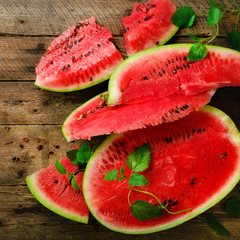 Slices of watermelon with mint leaves on wooden background. Detox and vegetarian concept. Top view,...