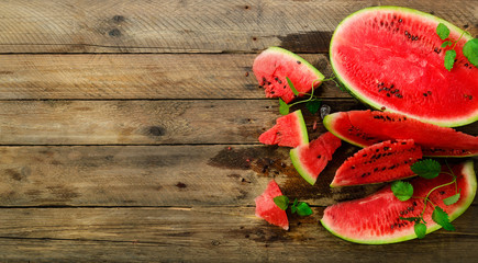 Slices of watermelon with mint leaves on wooden background. Detox and vegetarian concept. Top view, flat lay, copy space, banner