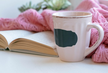 Mug of black coffee wrapped in warm scarf on wooden board. Top view, vintage style, Still life.