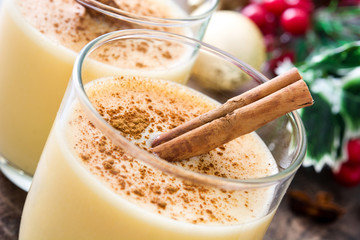 Homemade eggnog with cinnamon on wooden table. Typical Christmas dessert.
