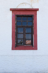 Old red window on a white wall, Greece.
