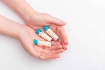 Woman hands holding a bottle with homeopathic pills on white background