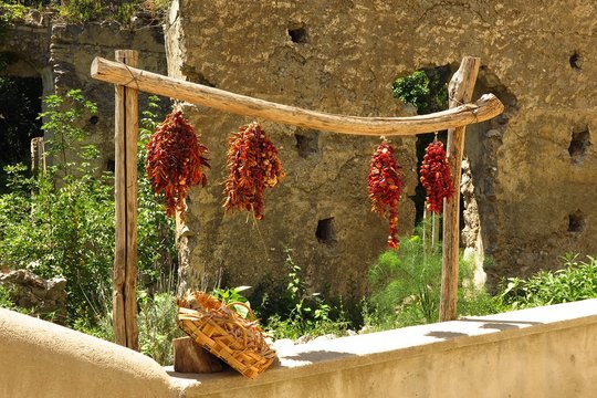 sun dried tomatoes hanging in the sun with rustic stone wall backdrop